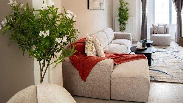 A living room with a beige sofa, a red throw blanket, a round coffee table, and a potted plant. - One Lux Stay 3BR / 2.5ba With Kids Room at Antwerp Near Central Station (Antwerp)