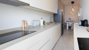 A modern kitchen with white cabinetry, a black induction cooktop, a built-in oven, and a stainless steel refrigerator. - One Lux Stay 3BR / 2.5ba With Kids Room at Antwerp Near Central Station (Antwerp)