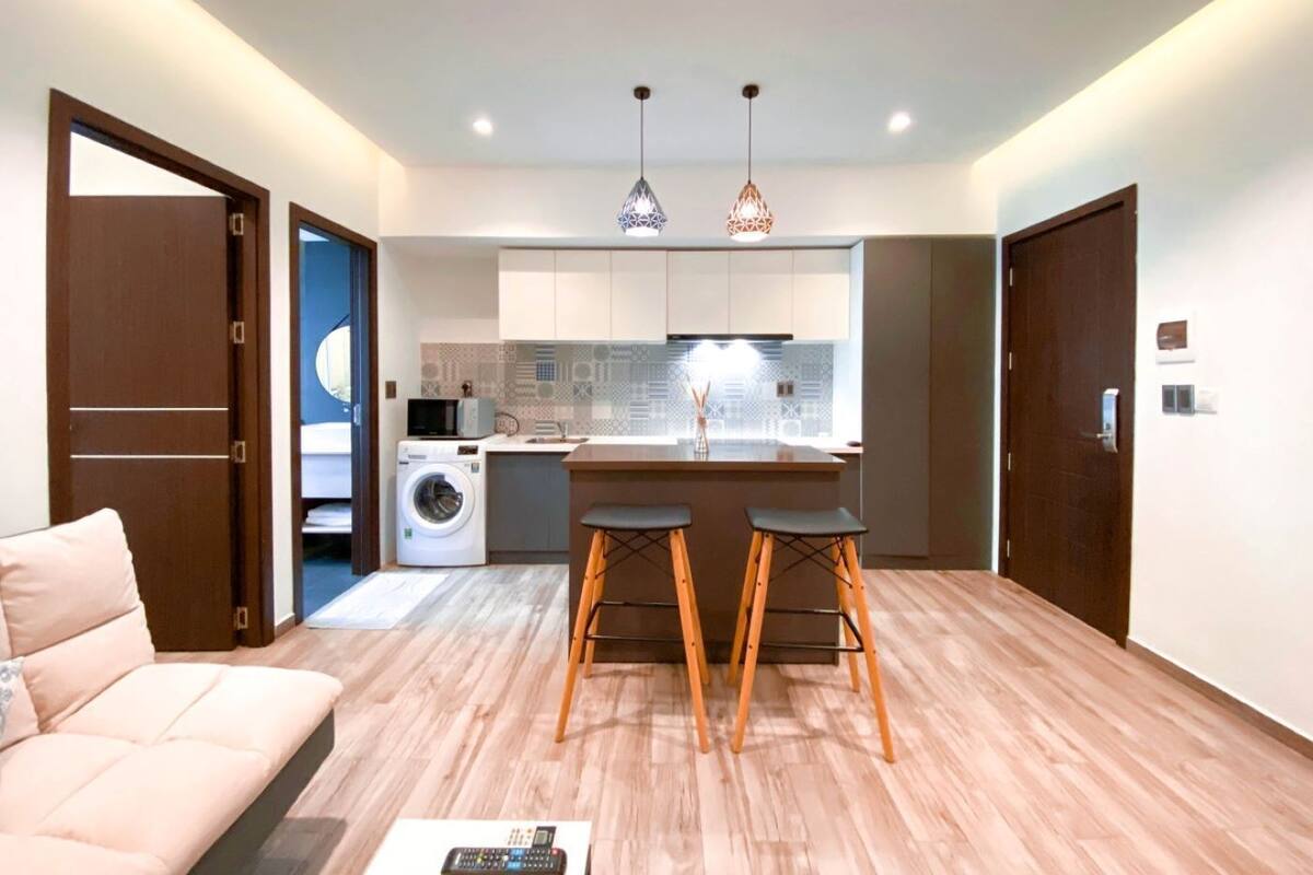 A modern apartment with a living area, kitchenette, and a washing machine.