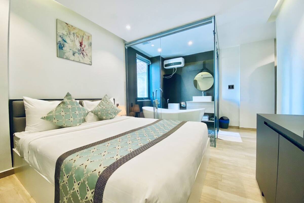 A modern hotel room with a large bed, a bathroom with a bathtub, and a large window.