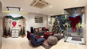Uma sala de estar moderna com um sofá, pufes, um pinheiro de Natal e uma lareira.