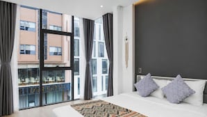 Un hotel moderno con una cama grande, vistas a la ciudad y un balcón con mobiliario exterior.