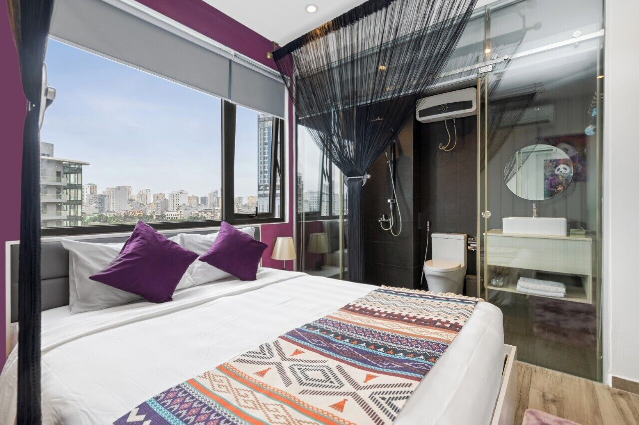 A modern bedroom with a large bed, a shower, and a view of the city.