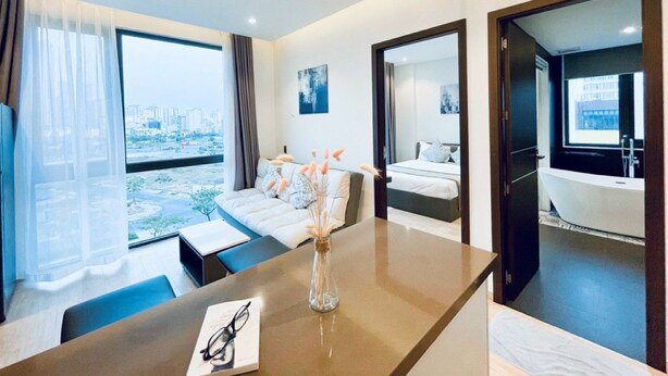Una habitación de hotel moderna con un ventanal grande, un sofá, una mesa de comedor y un baño.