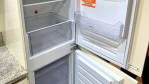 Frigorifero aperto con diversi ripiani e un biglietto sulla porta.