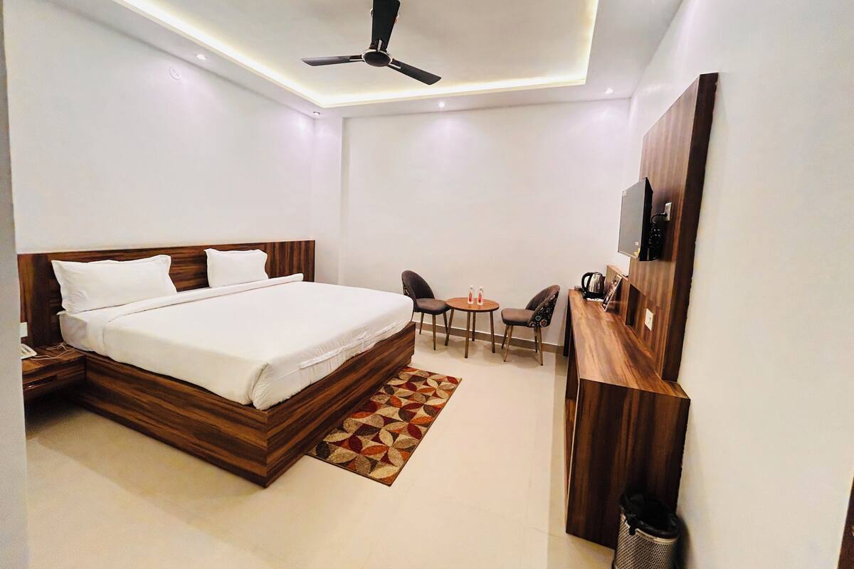 Une chambre d’hôtel moderne dotée d’un grand lit, d’un ventilateur de plafond, d’un petit coin salon et d’un téléviseur fixé au mur.