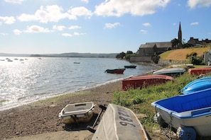 A lakeside view with boats, a church, and a stone wall. - Beautiful House With Garden (Landevennec)