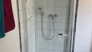 Een douche, handdoeken, zeep, toiletpapier