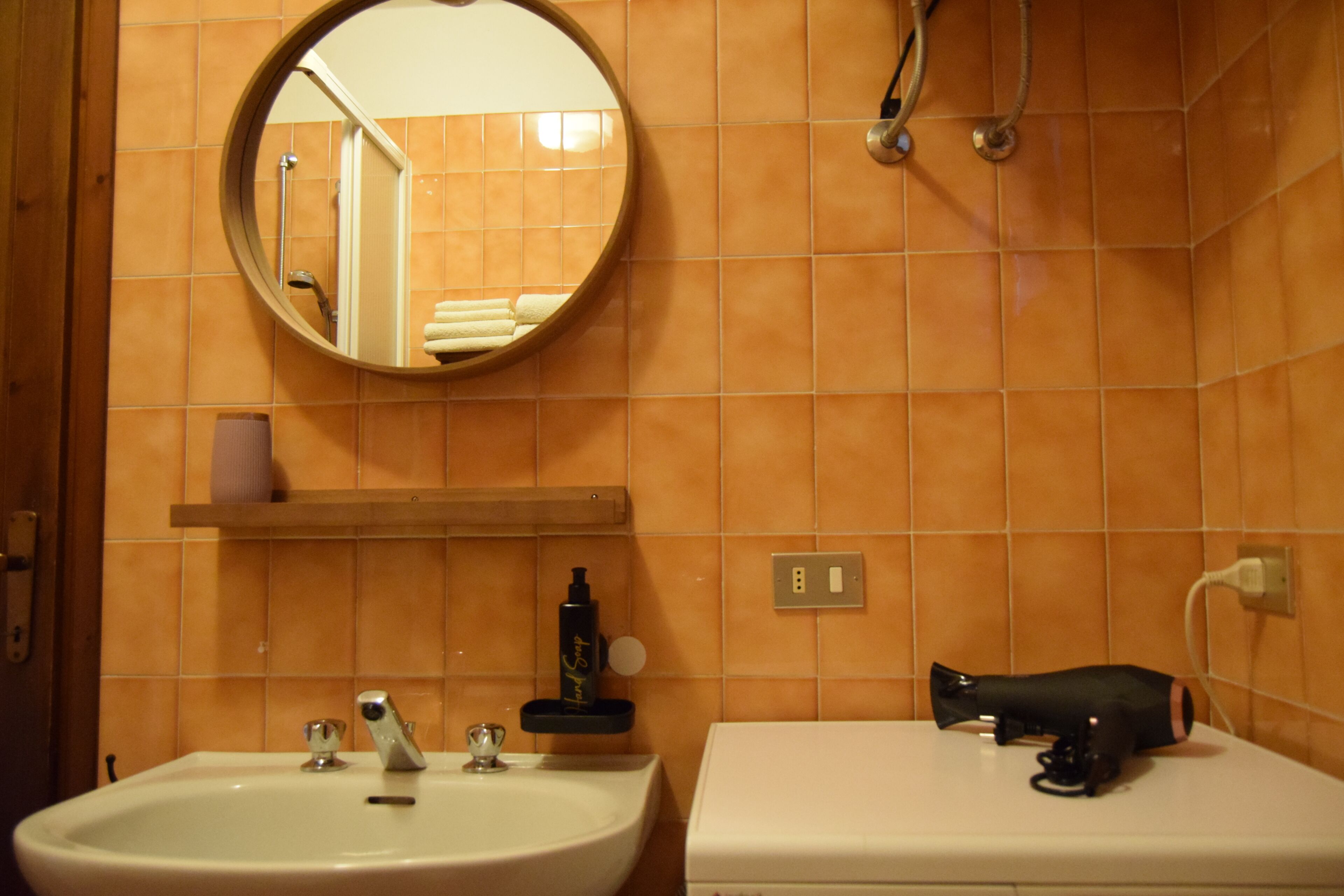Ein Badezimmer mit Waschbecken, Spiegel und einem Fön auf der Ablagefläche.