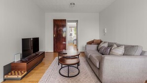 Un salon équipé d’un téléviseur, d’un canapé, d’une table basse et d’une porte donnant sur une autre pièce.