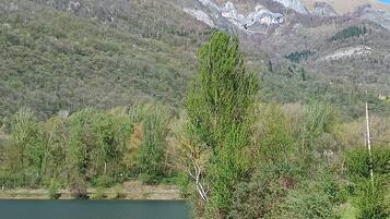 A lake with mountains in the background, a grassy area, and a bench.