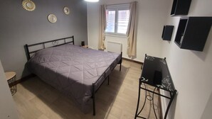 Un dormitorio con cama, escritorio, radiador y ventana con cortinas.