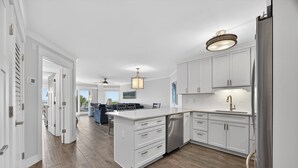 A modern kitchen with white cabinetry, a stainless steel refrigerator, and a central island. - New! Gorgeous Oceanfront 208 Sea Cloisters 2 BR Pool Beach Bikes and Beach Gear (Hilton Head Island)