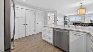 A modern kitchen with white cabinetry, a stainless steel refrigerator, and a dishwasher. - New! Gorgeous Oceanfront 208 Sea Cloisters 2 BR Pool Beach Bikes and Beach Gear (Hilton Head Island)