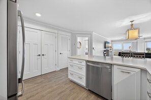 A modern kitchen with white cabinetry, a stainless steel refrigerator, and a dishwasher. - New! Gorgeous Oceanfront 208 Sea Cloisters 2 BR Pool Beach Bikes and Beach Gear (Hilton Head Island)