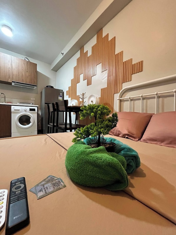A hotel room with a bed, a small green plant, a remote control, and a QR code on the bed. - Room-aesthetic, Cozy and Modern Pool and (Lapu-Lapu)