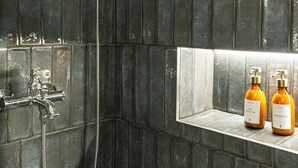 A shower with a handheld showerhead and a wall-mounted faucet. There are two bottles of shampoo on a shelf. - Normandy Cottage City Center charming apartment (Évreux)