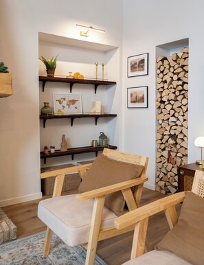 Une pièce chaleureuse avec une chaise en bois, une petite table, un globe terrestre, des photos encadrées et un mur recouvert de bûches empilées.