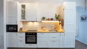 A modern kitchen with white cabinetry, a built-in oven, a microwave, a sink, and pendant lighting. - Normandy Cottage City Center charming apartment (Évreux)