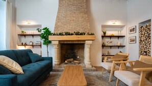 A living room with a fireplace, a sofa, a coffee table, and wooden chairs. - Normandy Cottage City Center charming apartment (Évreux)
