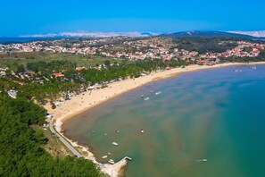 An aerial view of a coastal town with a beach, boats, and buildings. - Seafront Apartment on the Island of Rab (Rab)