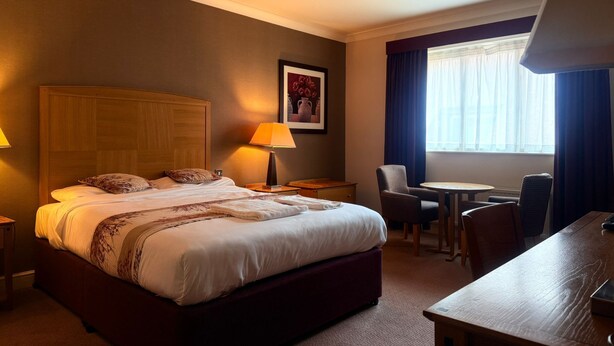 Une chambre d’hôtel avec un grand lit, des lampes de chevet, un bureau et une chaise.
