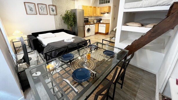 A modern hotel room with a glass dining table, a bed, a kitchen area, and a staircase. - Espace Barillerie 12 - Old Town (Nice)
