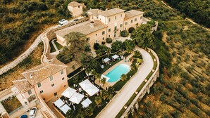 Oversigtsbillede af et hotel med en swimmingpool, terrasserede haver og en bakke i baggrunden.