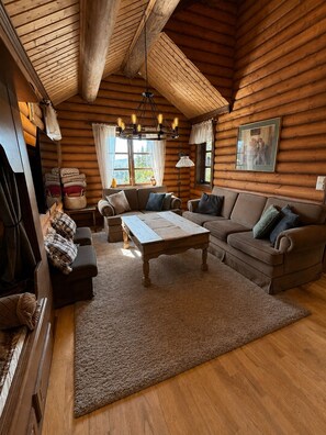 A log cabin interior with a wooden ceiling, a sofa set, a coffee table, and a fireplace. - Cozy family cabin with sauna! Pets are allowed, up to 13 beds. (Buskerud)