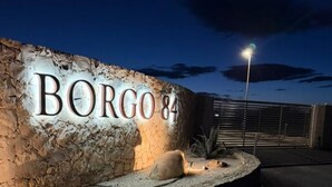 Um muro de pedra com o nome 'BORG 84' iluminado ao anoitecer.