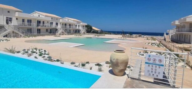 Um resort com piscina, área de praia e um edifício com várias varandas.