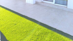 Um edifício moderno com grandes portas de correr de vidro, um teto plano e um pátio pavimentado.