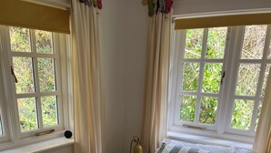 A bed with striped bedding, a pillow with a flower design, and a bedside lamp. - Amazing 4bedroom dog/family friendly lodge with hottub/fire bowl in Cornish wood (Bodmin)