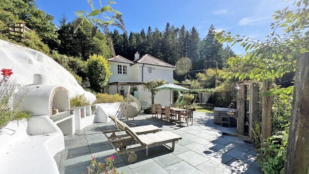 A house with a patio, outdoor seating, and a barbecue area. - Amazing 4bedroom dog/family friendly lodge with hottub/fire bowl in Cornish wood (Bodmin)