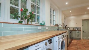 A kitchen with a washing machine, a wooden countertop, and a window with plants. - Amazing 4bedroom dog/family friendly lodge with hottub/fire bowl in Cornish wood (Bodmin)