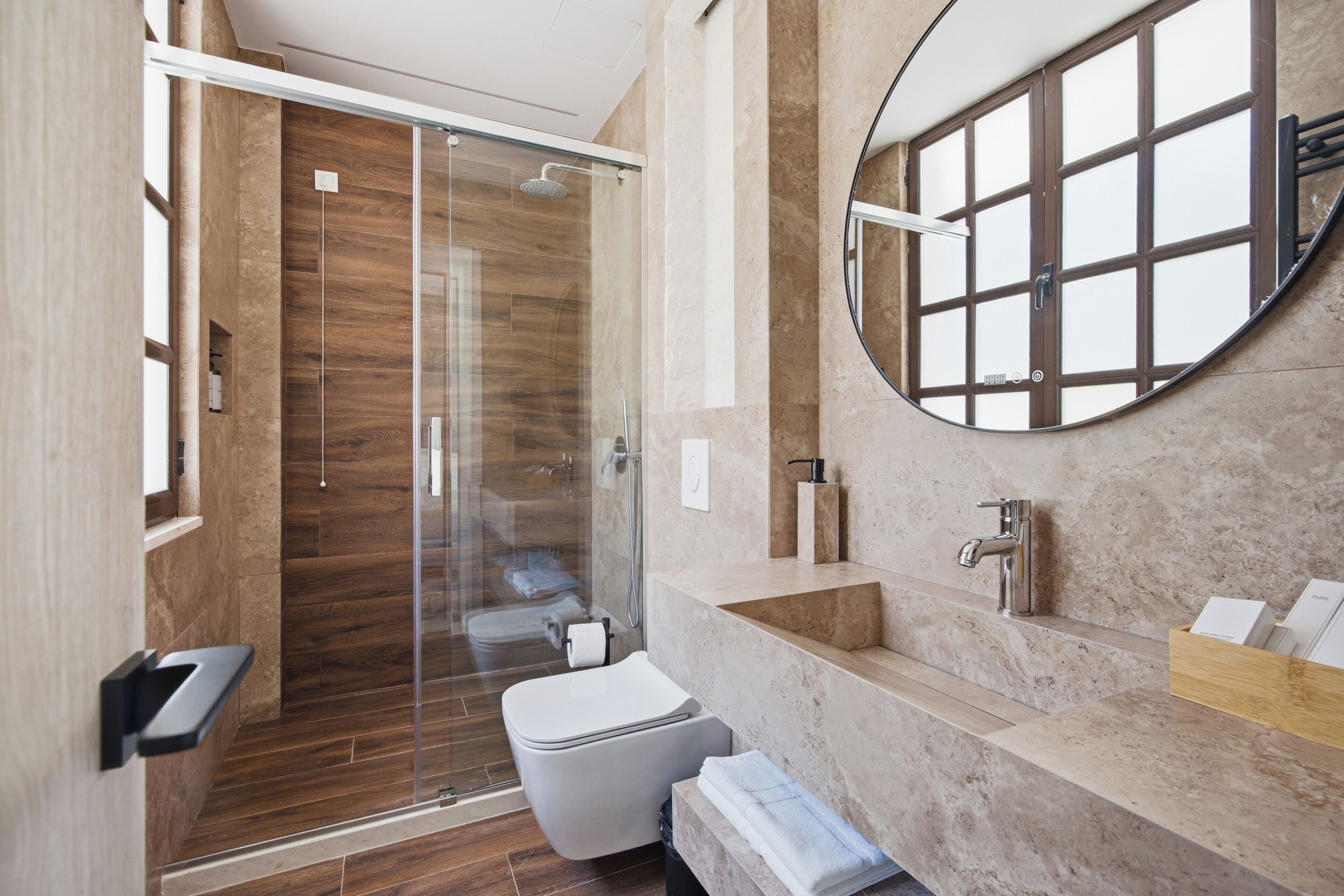 A modern bathroom with a glass-enclosed shower, a toilet, a sink, and a mirror.