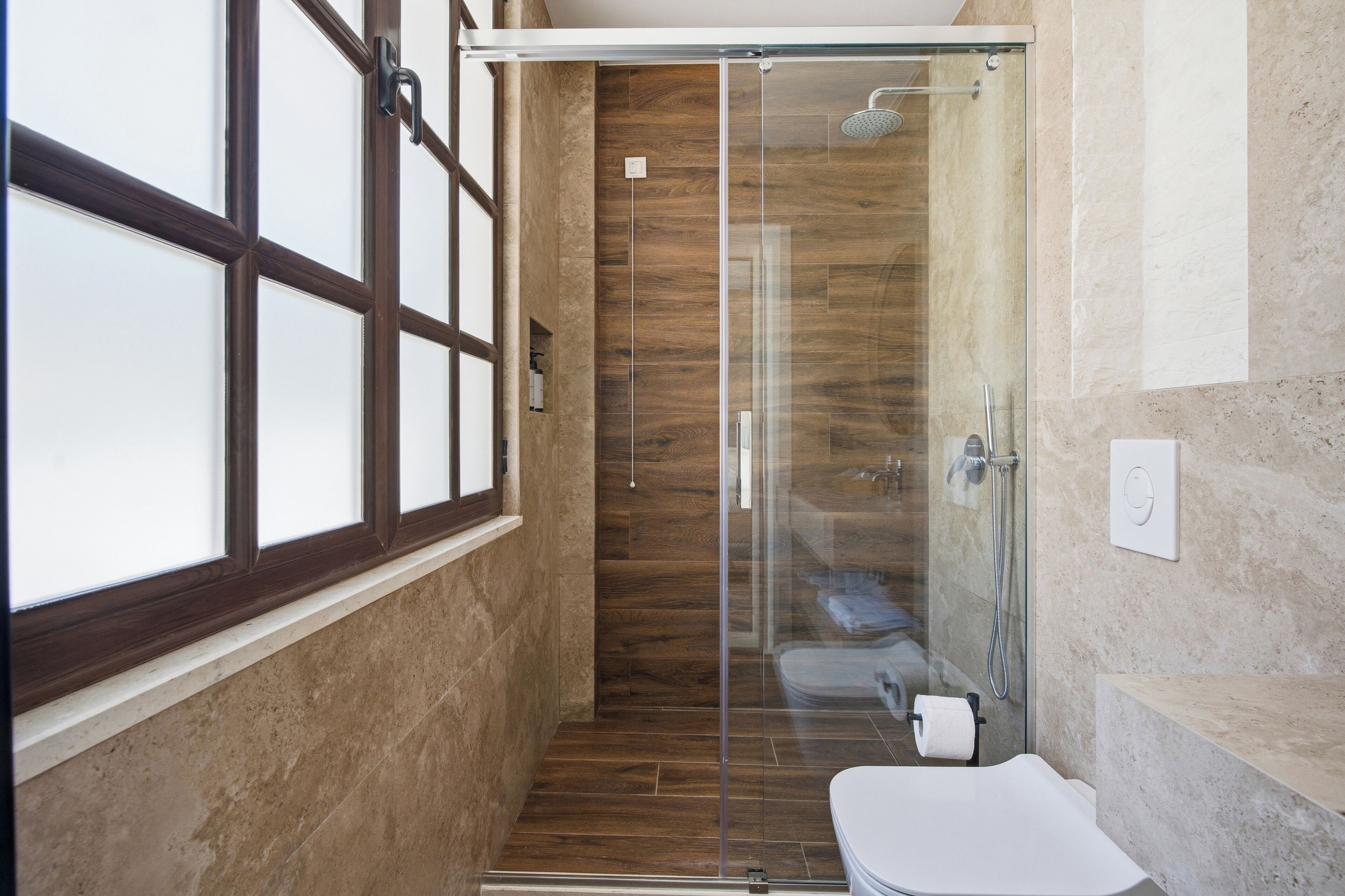Un baño moderno con cabina de ducha de vidrio, inodoro y lavamanos.