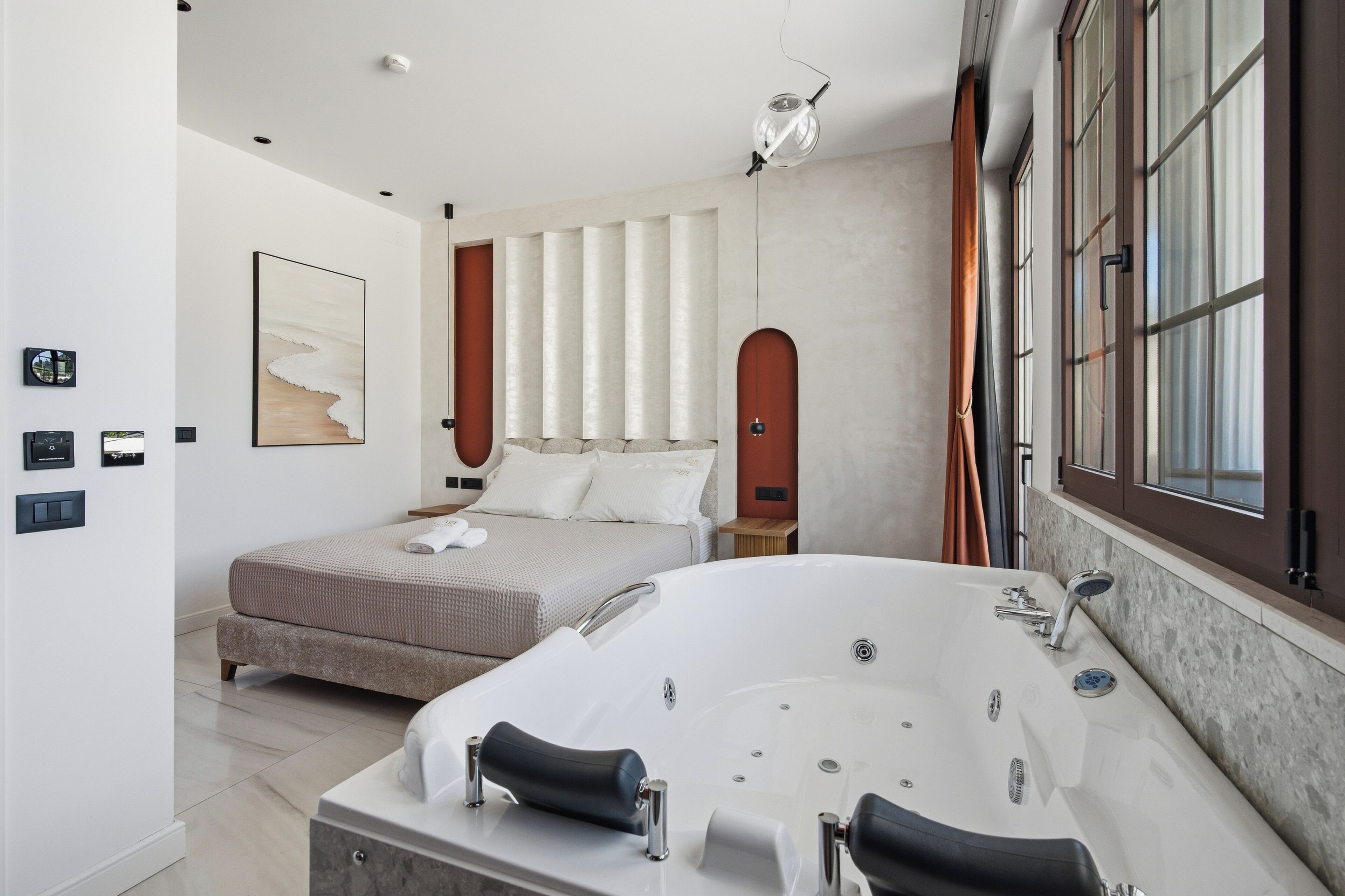 Un dormitorio moderno con una cama grande, una bañera y una ventana con cortinas.