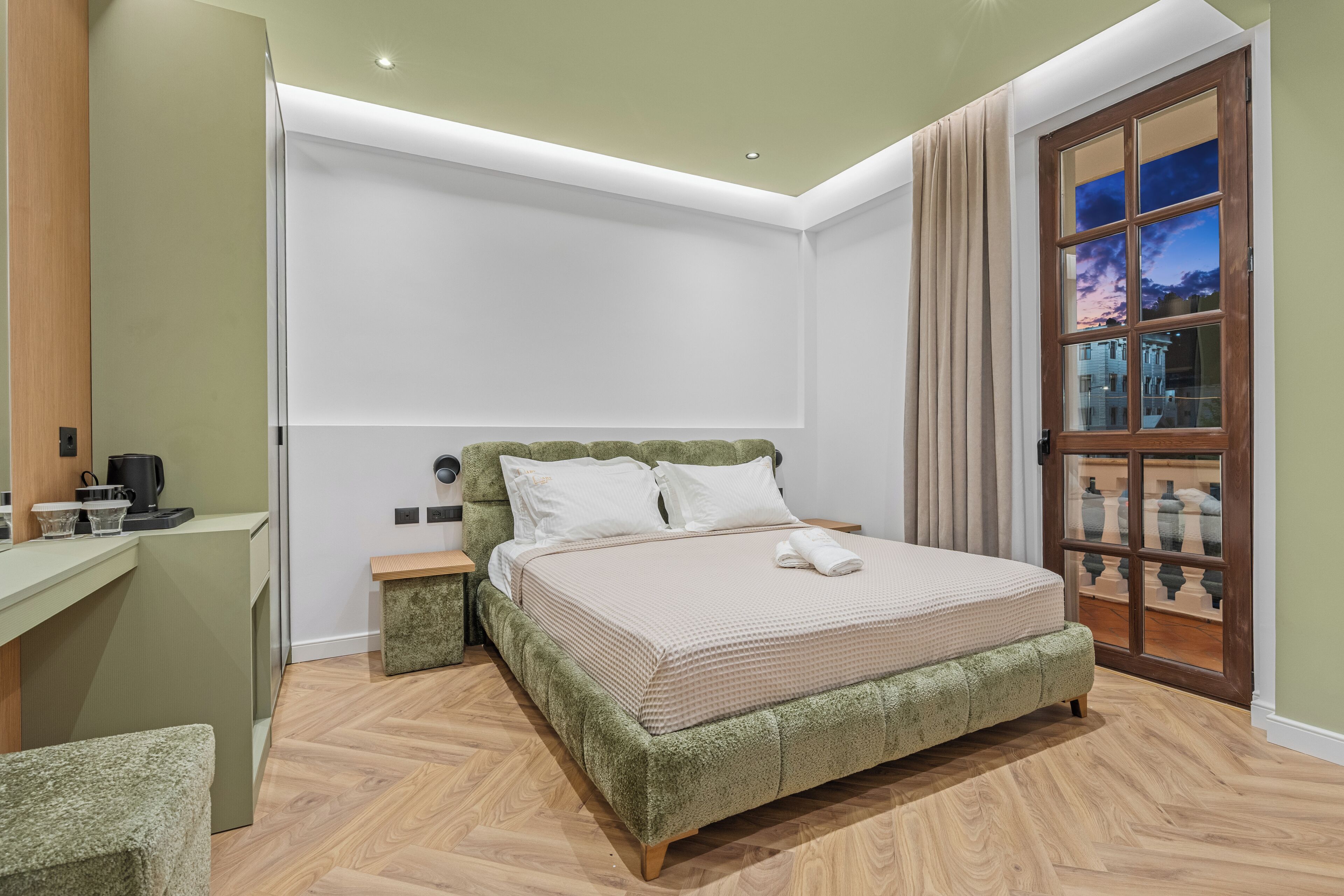 A bedroom with a bed, bedside tables, a desk, and a window with a view.