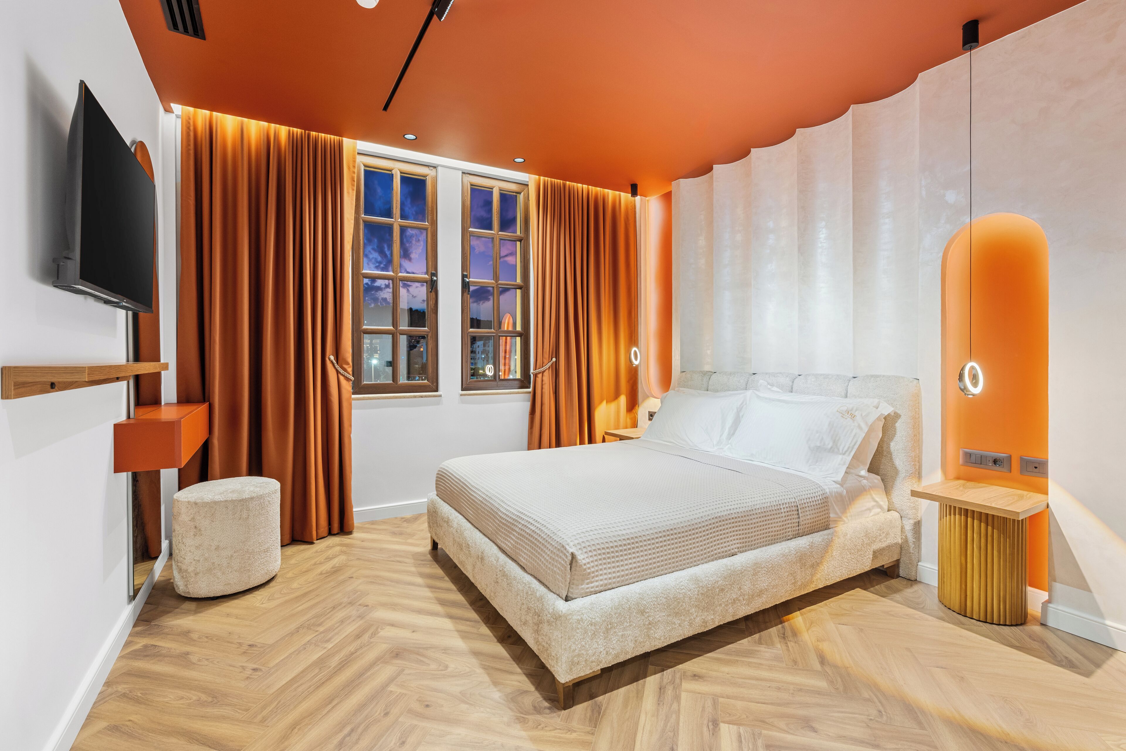 A modern bedroom with a bed, curtains, a TV, and a window.