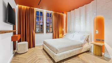 A modern bedroom with a bed, curtains, a TV, and a window.