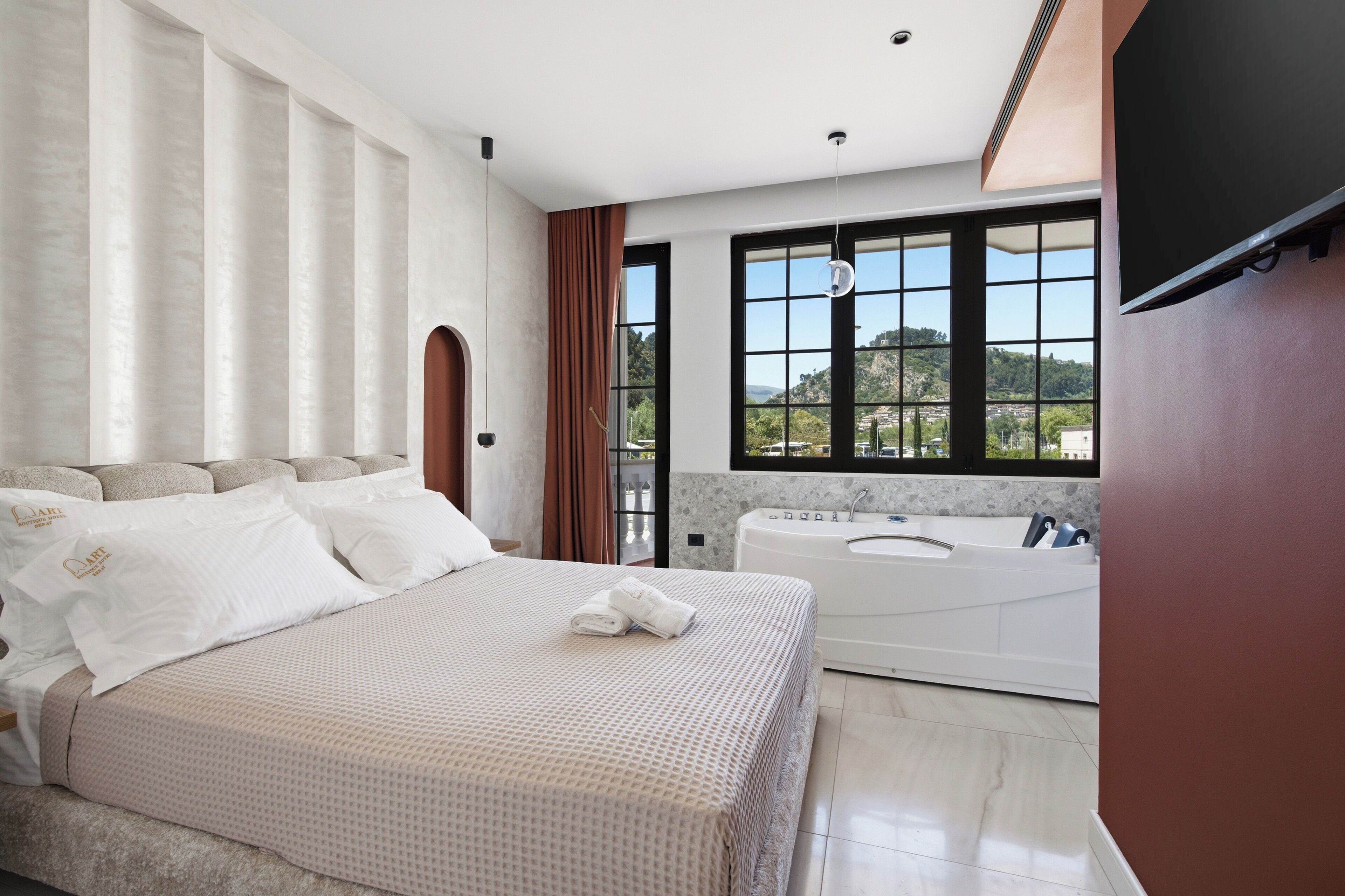 Un dormitorio con una cama grande, una bañera y vistas a un paisaje montañoso.