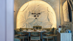Un coin repas avec une table ronde dressée pour quatre personnes, entourée de chaises rembourrées.