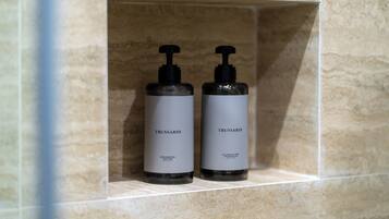 Dos ampolles de productes de cura de la pell Trussardi en un nínxol amb rajoles.