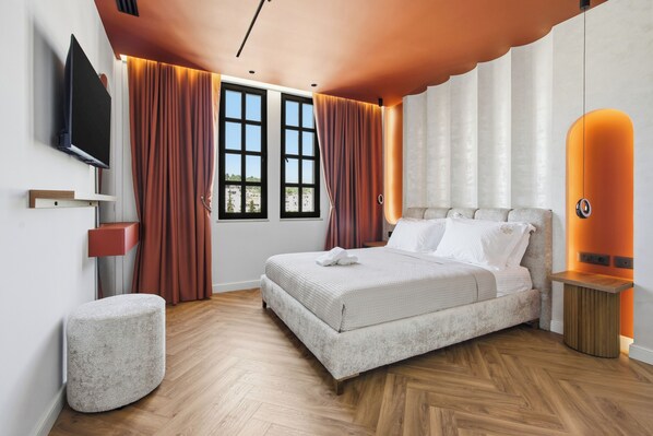 A modern bedroom with a bed, curtains, a TV, and a unique ceiling design.