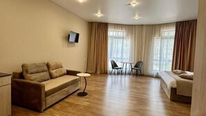 A spacious room with a sofa, a bed, a TV mounted on the wall, and a dining area with chairs. - MARCO Hotel (Goris)