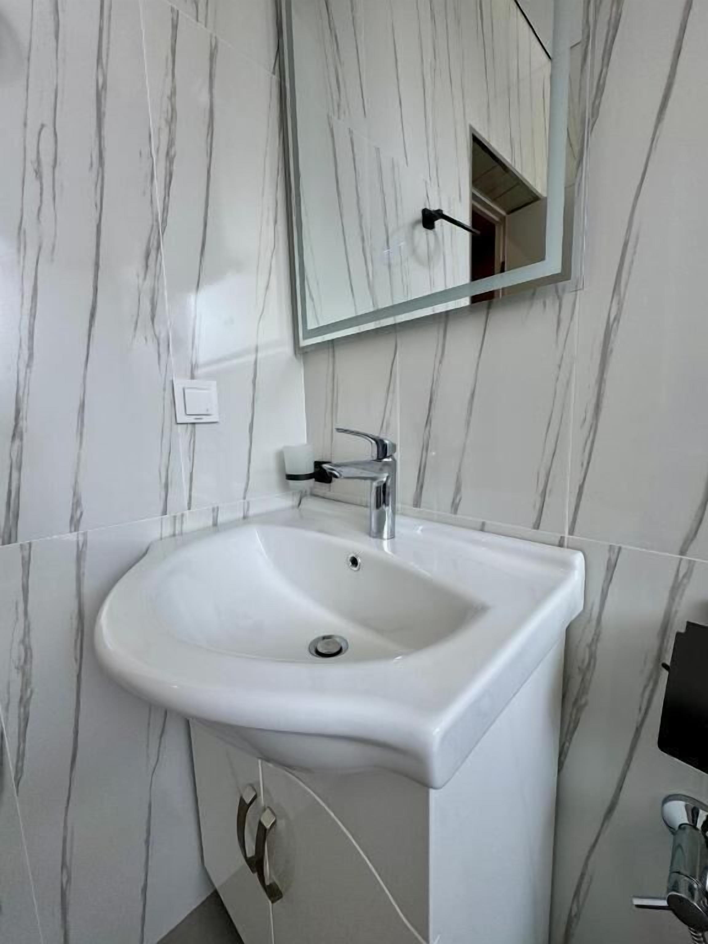 A bathroom with a white sink, a mirror, and marble-patterned walls.