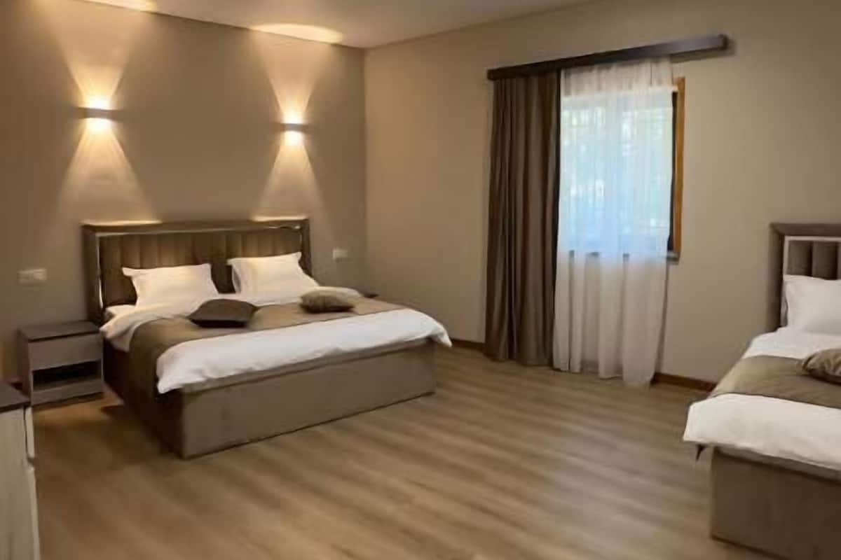 Una camera d'albergo con un letto grande, comodini, un armadio e una finestra con tende.