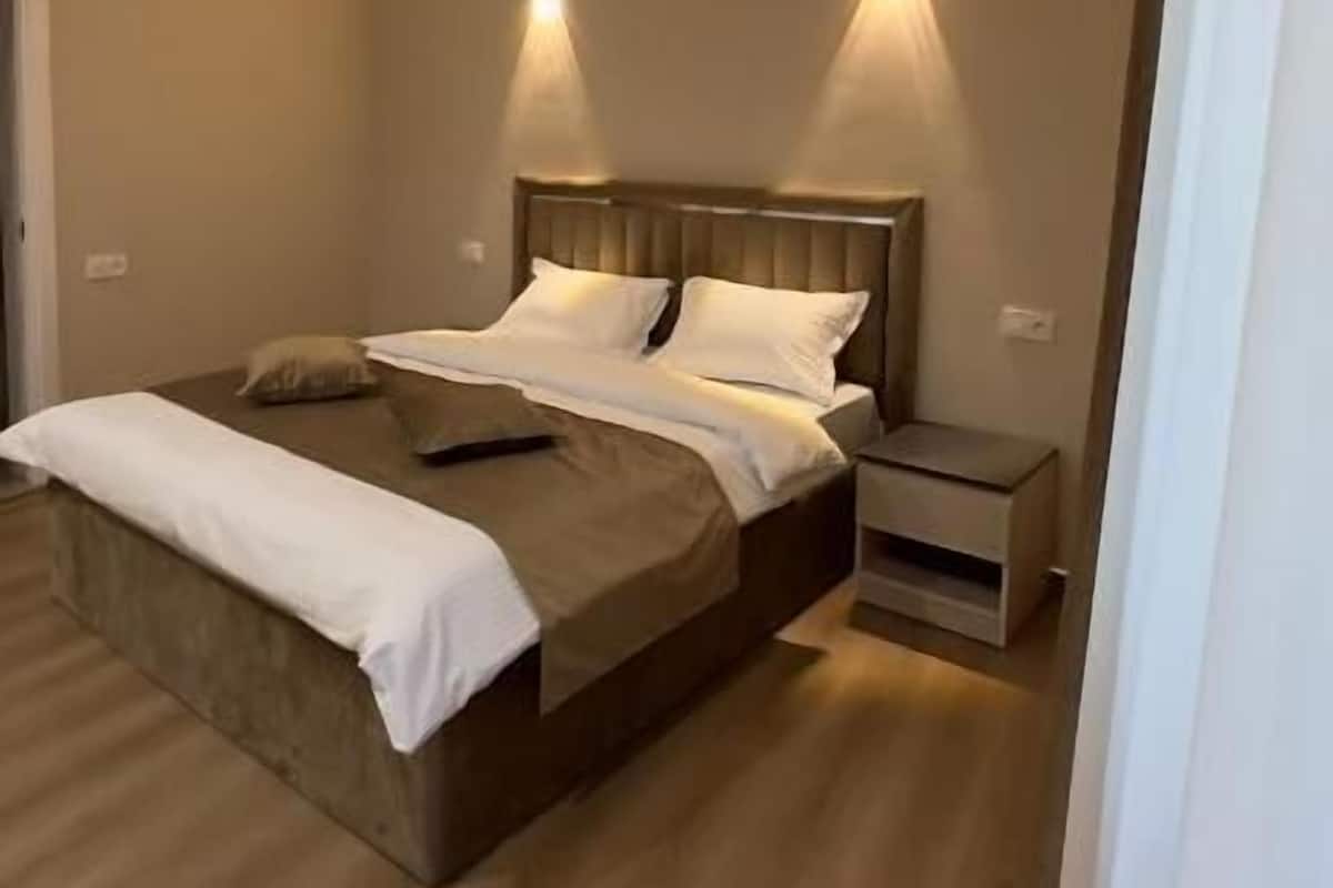 Una camera da letto con un letto, comodini e illuminazione a parete.