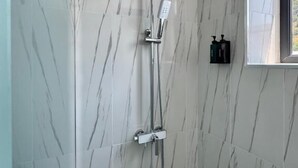 A modern bathroom with a shower, marble walls, and a window. - MARCO Hotel (Goris)